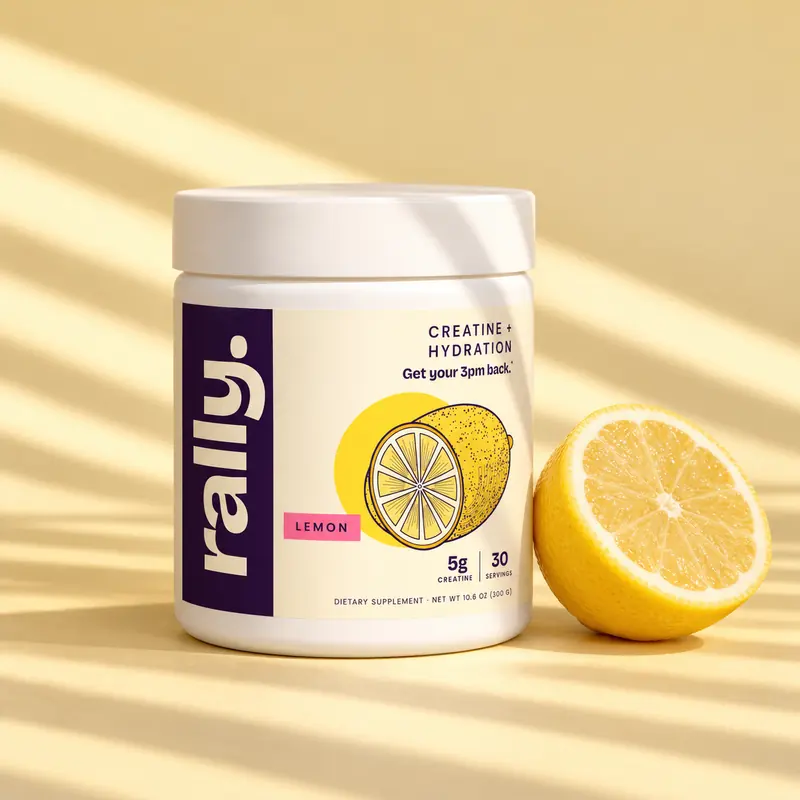 Rally Creatine Hydration lemon tub next to a halved lemon on a butter-yellow table